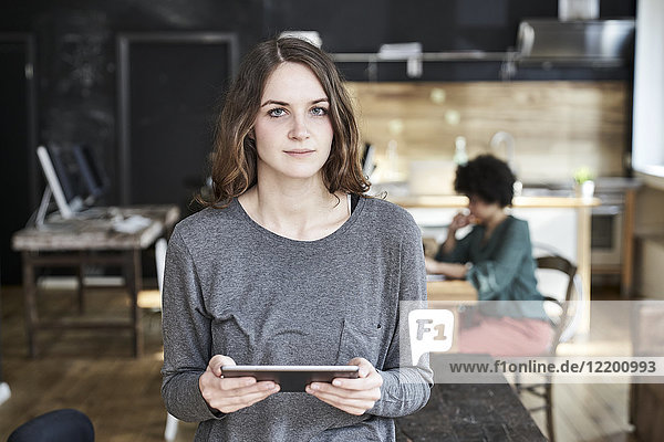 Portrait of young woman holding tablet in modern office