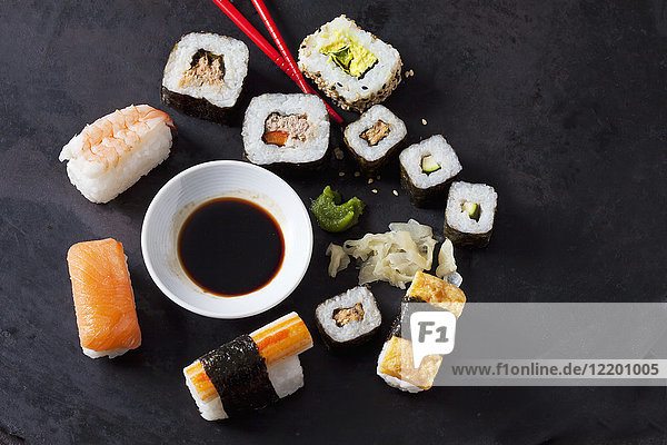 Sushi-Vielfalt mit Wasabi  Ingwer und Sojasauce auf dunklem Boden
