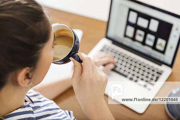 Young woman having a coffee break from working with laptop at home