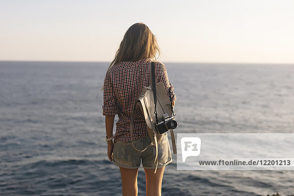 Indonesia  Bali  Lembongan island  young woman with camera at ocean coastline