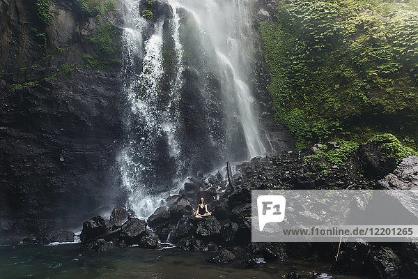 Indonesien  Bali  junge Frau beim Yoga am Wasserfall Sekumpul