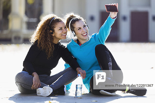 Two smiling sportive young women having a break taking a selfie