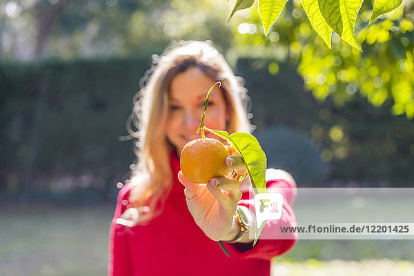 Junge Frau mit Mandarine im Garten
