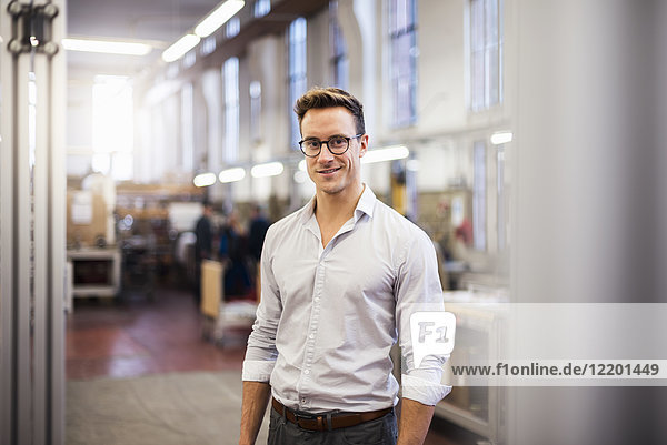 Portrait of smiling young businessman in factory
