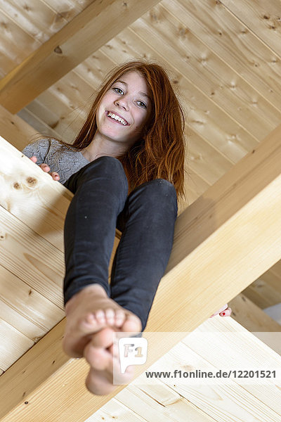 Portrait of laughing redheaded teenage girl sitting in attic