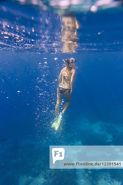 Frau mit Flossen und Schnorcheltauchen unter Wasser