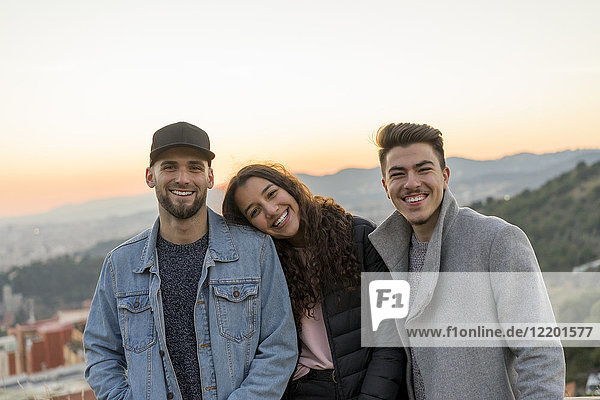 Porträt von drei glücklichen Freunden auf einem Hügel bei Sonnenuntergang