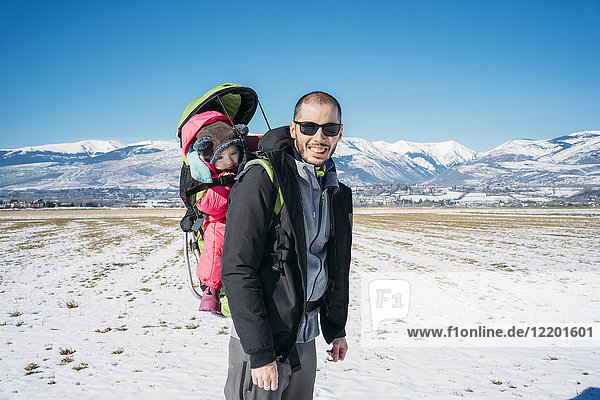 Spain  Puigcerda  father with baby girl in a kid carrier backpack during a hike at winter