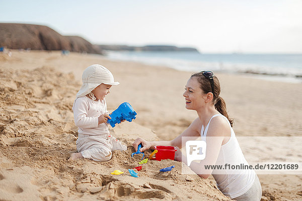 Mutter spielt mit kleiner Tochter am Strand