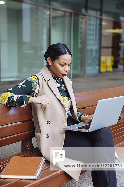 Geschäftsfrau auf der Bank sitzend mit Laptop