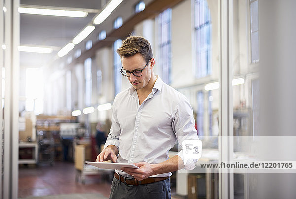Young businessman in factory using tablet