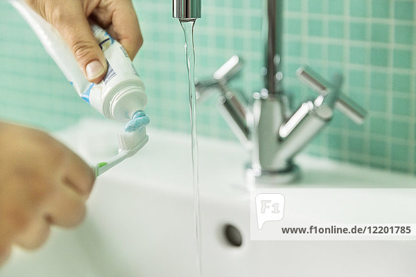 Hände setzen Zahnpasta auf Zahnbürste im Bad