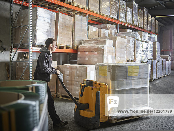Man operating pallet jack in storehouse