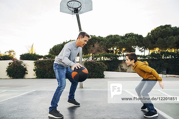 Vater und Sohn spielen Basketball auf einem Freigelände