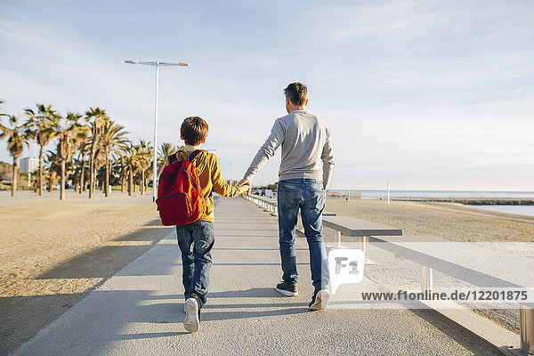 Father and son walking on beach promenade