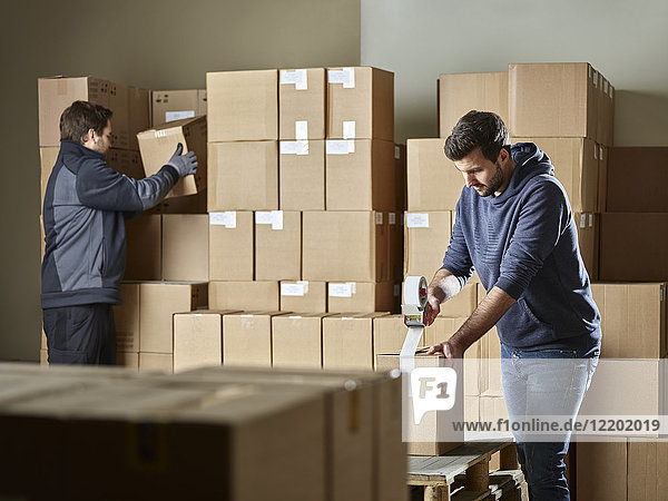 Arbeiter verschließen Pakete mit Paketband