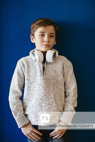 Portrait des Jungen mit Kopfhörer an der blauen Wand