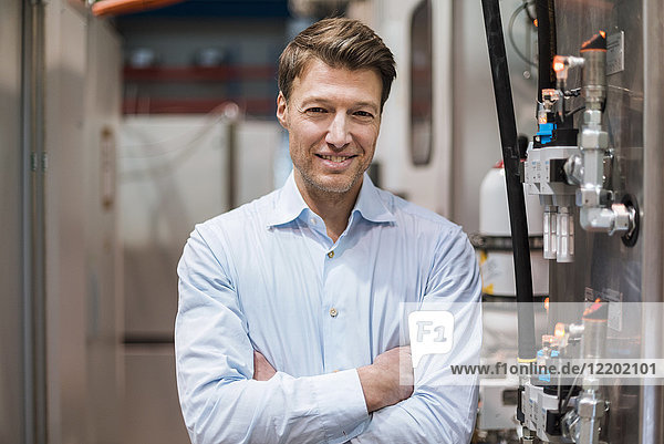 Porträt des lächelnden Geschäftsmannes an der Maschine in der Fabrik