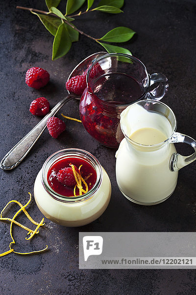 Glas Pudding mit Vanillesauce und Himbeersauce garniert mit Himbeer- und Orangenschale