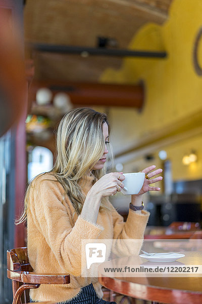 Nachdenkliche junge Frau in einem Café mit einer Tasse Kaffee