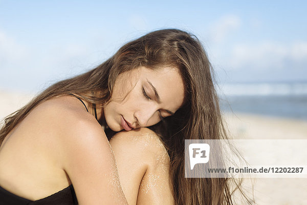 Attraktive junge Frau mit geschlossenen Augen am Strand