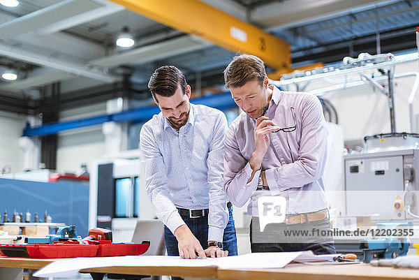 Two men in factory looking at plan