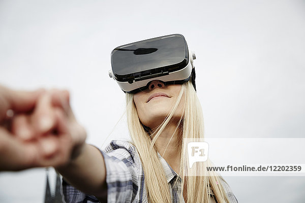 Frau mit einer Virtual Reality Brille  die Händchen hält
