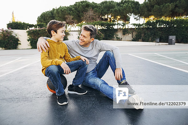 Father embracing son on basketball outdoor court