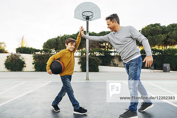 Vater und Sohn High Fiving auf dem Basketball-Außenplatz