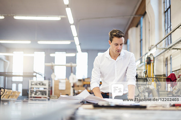Young businessman in factory working on plan