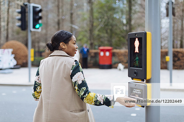 UK  London  Frau drückt Taste des Fußgängerlichts