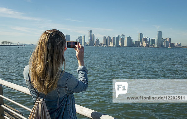 USA  New York  woman taking cell phone picture of New Jersey skyline