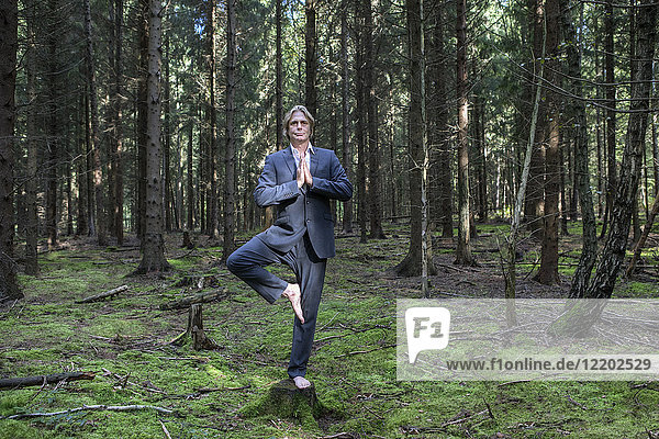 Geschäftsmann beim Yoga im Wald