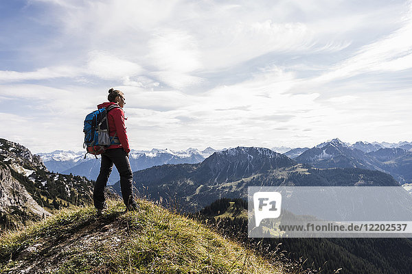 Austria  Tyrol  young woman standing in mountainscape looking at view