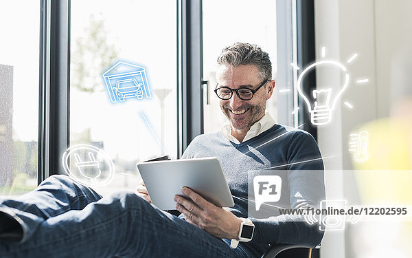 Ein Mann sitzt im Büro und benutzt ein digitales Tablett  um sein intelligentes Zuhause zu steuern.