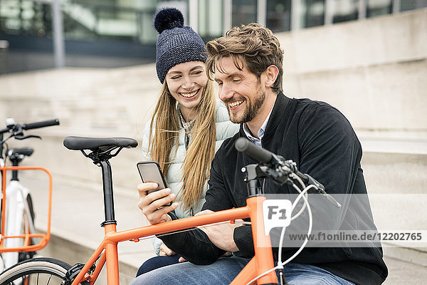 Lächelndes Paar mit Fahrrädern und Handy in der Stadt