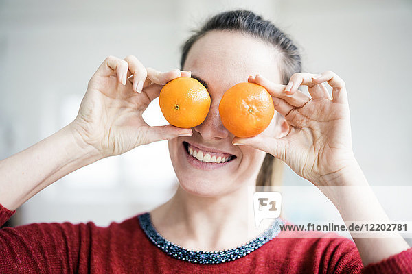 Lachende Frau  die ihre Augen mit Orangen bedeckt.