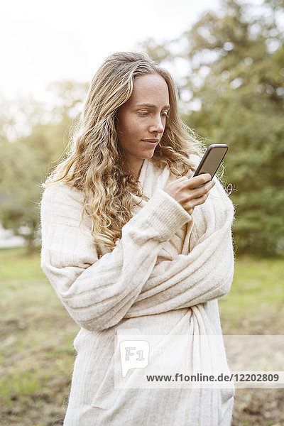 Blond woman in rural landscape looking at cell phone