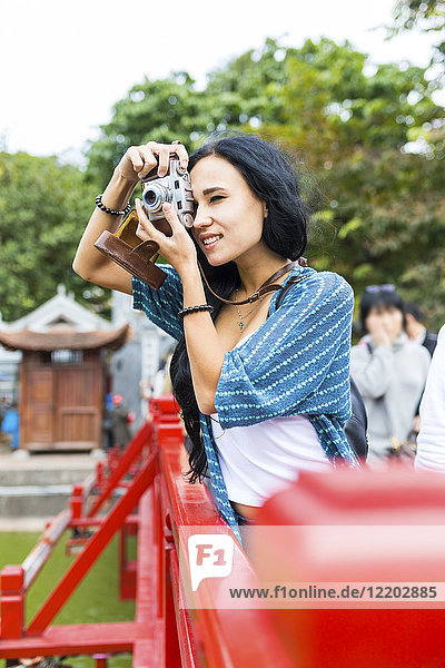 Vietnam  Hanoi  junge Frau beim Fotografieren mit altmodischer Kamera