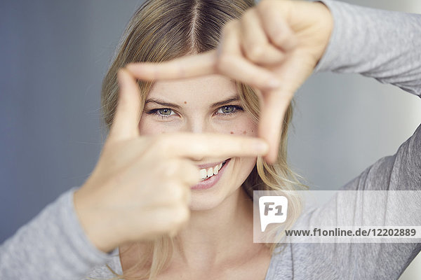 Porträt einer lachenden Frau  die mit ihren Fingern einen Rahmen baut.