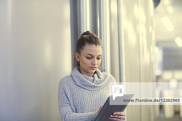 Porträt einer ernsthaften jungen Frau mit Tablette im Büro