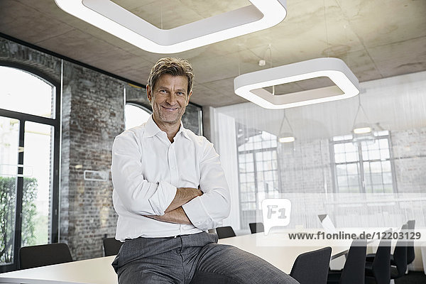 Portrait of confident mature businessman in conference room of modern office