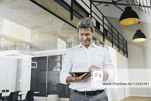 Portrait of mature businessman using tablet in modern office