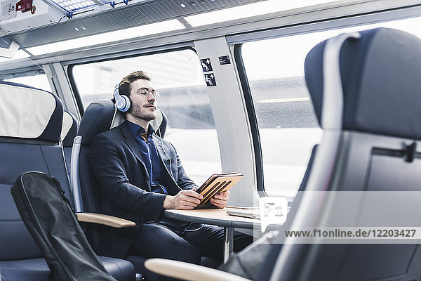 Businessman in train relaxing listening to music
