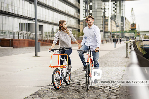 Smiling couple riding bicycle in the city