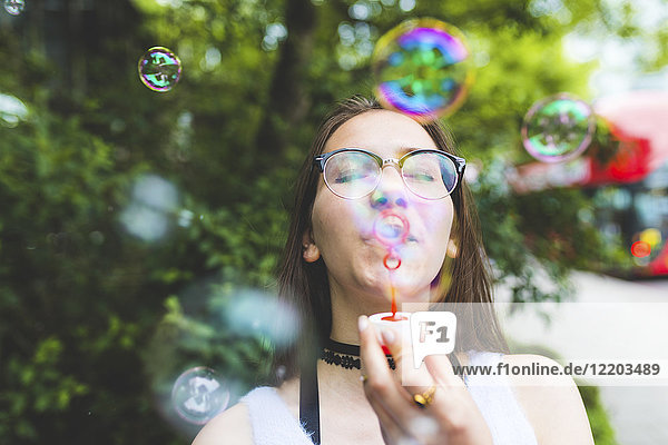 Teenage girl blowing soap bubbles outdoors