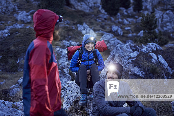 Lächelnde Bergsteiger mit Scheinwerfern in den Bergen bei Einbruch der Dunkelheit