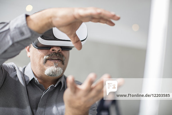 Man shaping with his hands wearing VR glasses in office