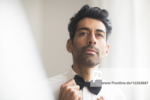 Portrait of man adjusting his bow tie