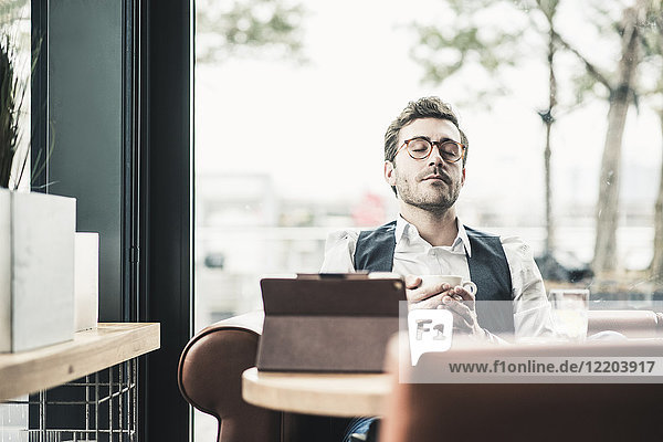 Junger Mann in einem Café mit Tablettentasse Kaffee zum Entspannen